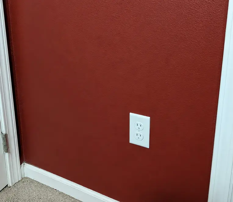 Repaired maroon drywall wall after patching, finishing, and painting